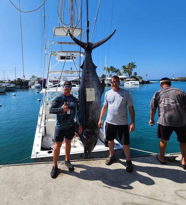 Two men standing next to a large fish on a boat