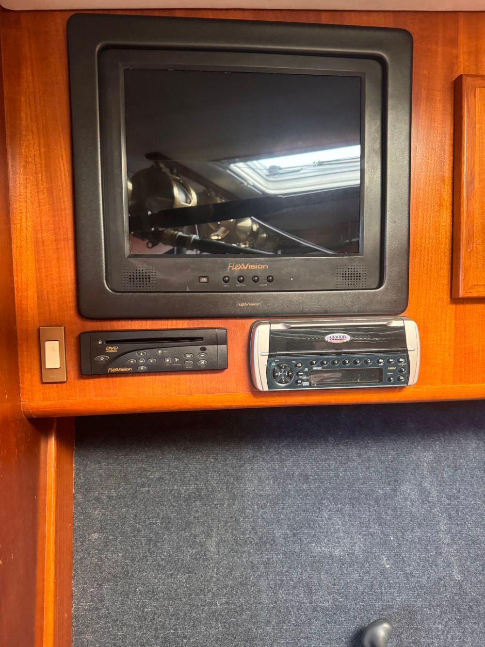 A television is mounted on a wooden wall next to a radio.