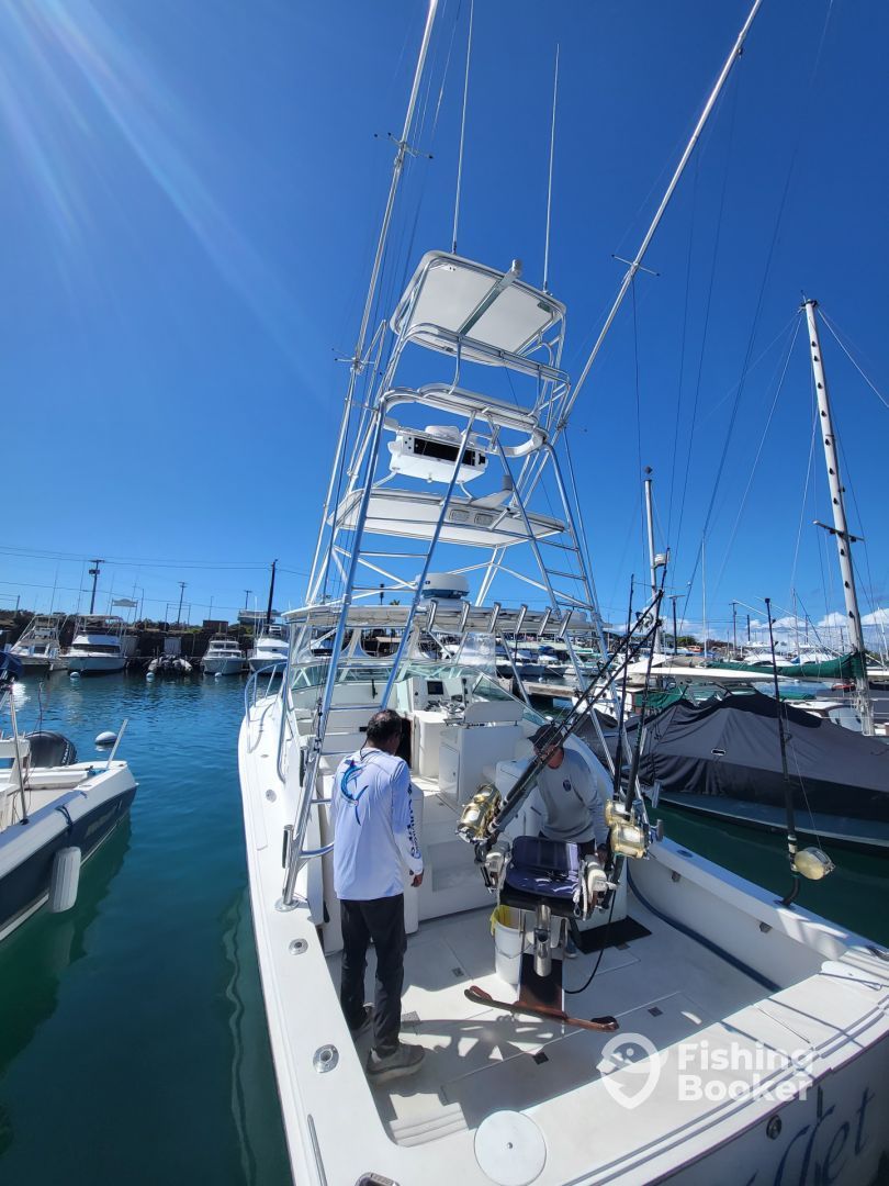 A man is standing on the deck of a boat in a marina.