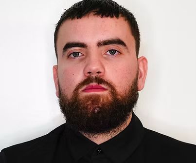 A man with a beard and red lips is wearing a black shirt.