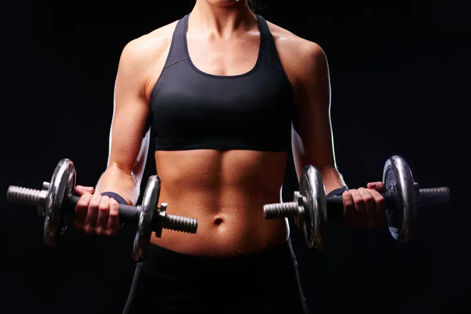 A woman is holding two dumbbells in her hands.