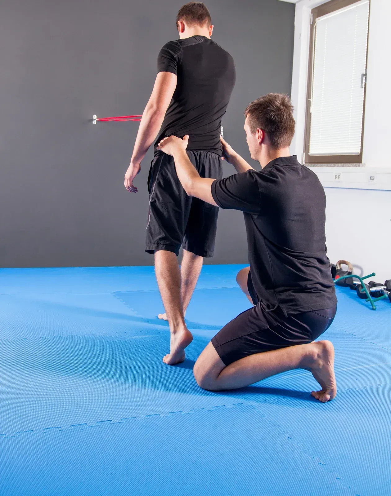 A man is measuring another man 's waist on a blue mat.