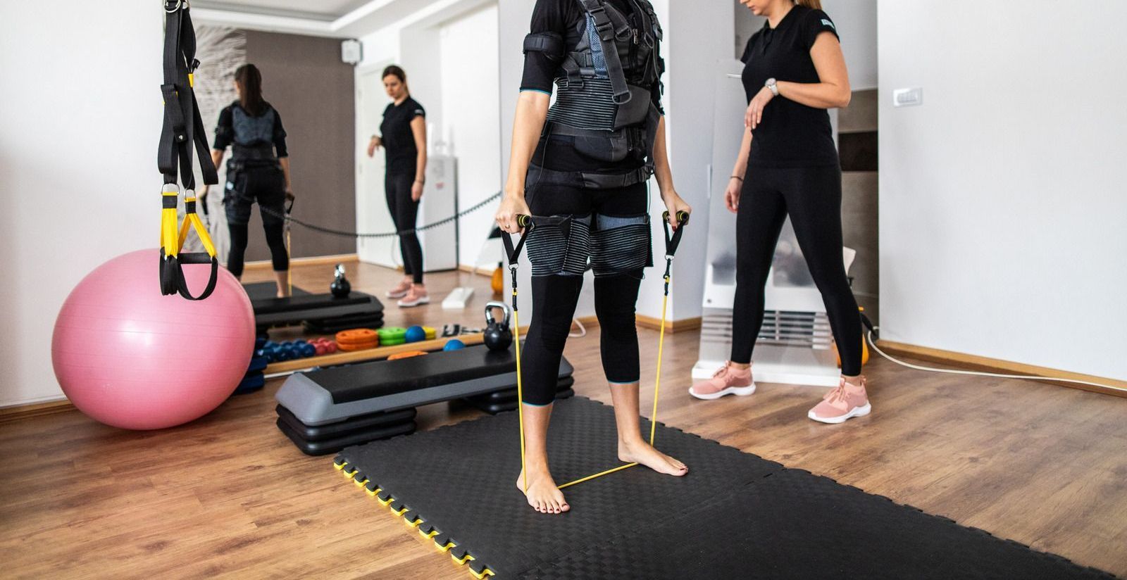 A woman is doing exercises in a gym with a trainer.