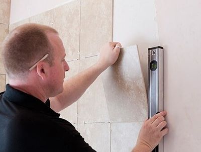 A Tiler Lining Up A Tile To Place On The Wall — Remodeling Contractor in Denver, CO