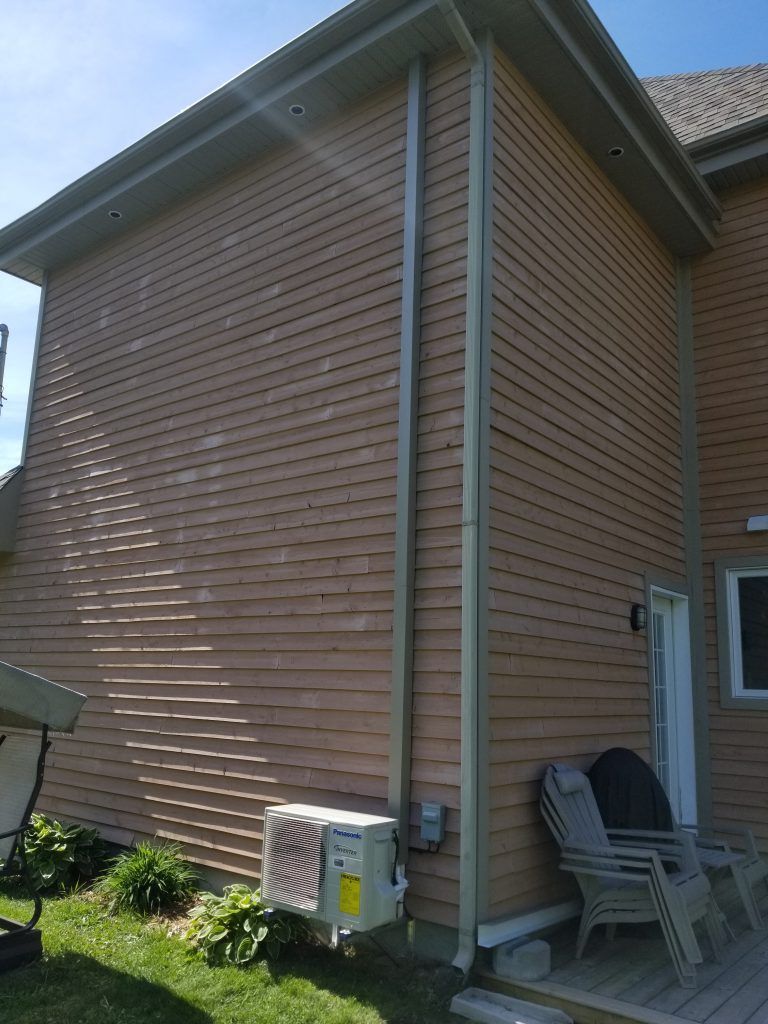 Une maison avec une chaise et un parasol sur le côté