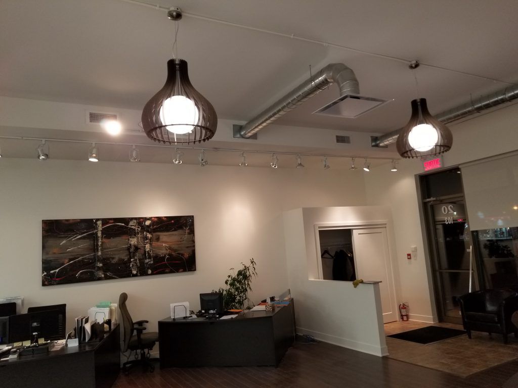 Une pièce avec un tableau sur le mur et deux lampes suspendues au plafond