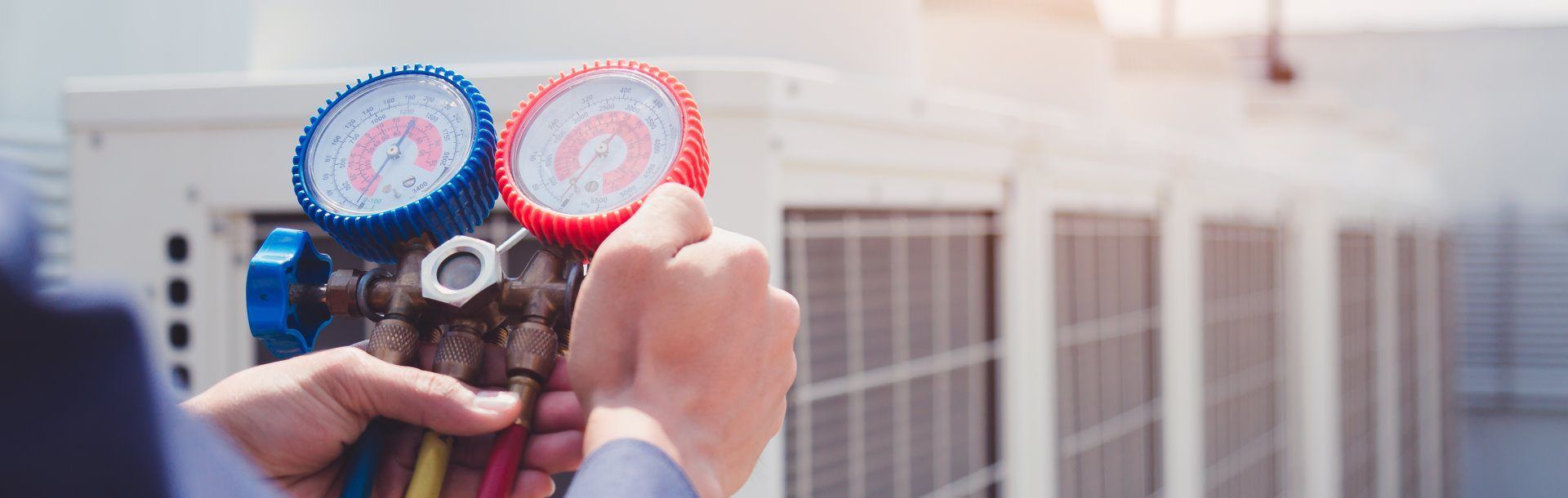 Technicien CVC utilisant des manomètres pour vérifier un climatiseur.