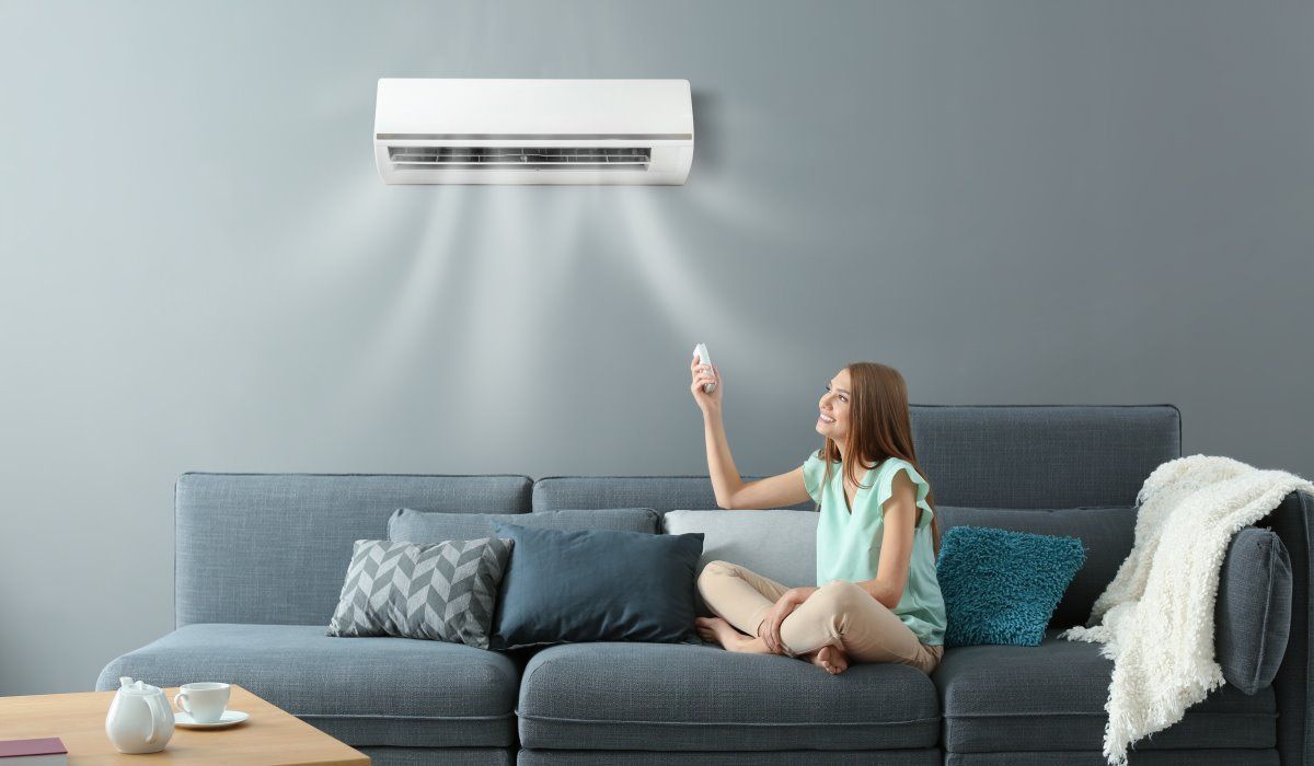 Une femme est assise sur un canapé tenant une télécommande.