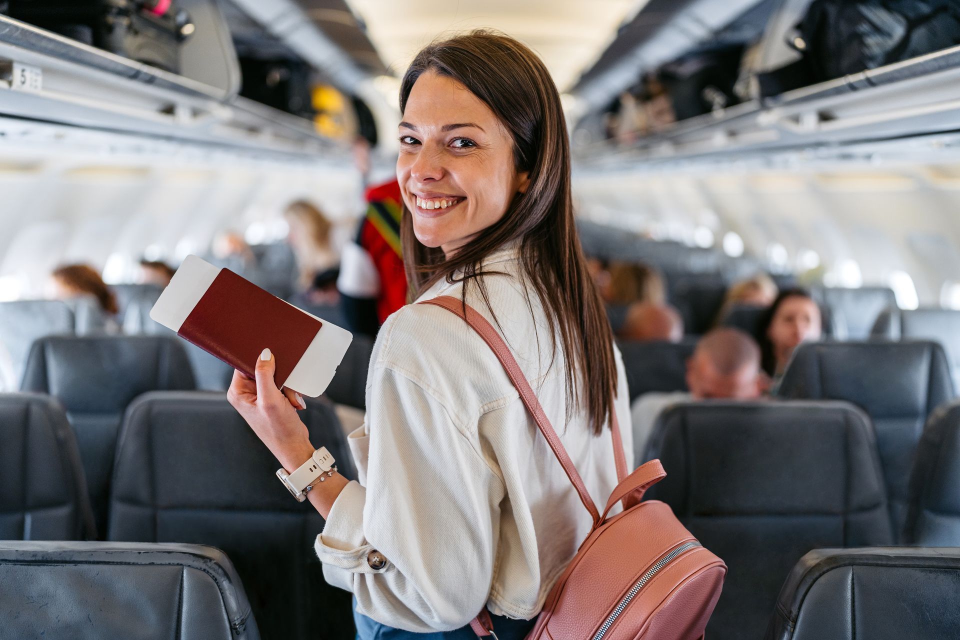 A woman is holding a passport and boarding pass on an airplane. A woman is holding a passport and boarding pass on an airplane.