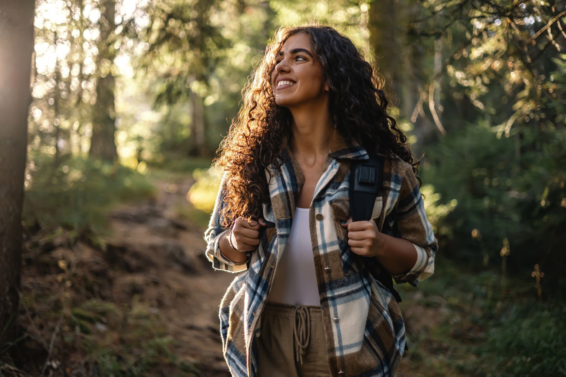 A woman is walking through the woods with a backpack. A woman is walking through the woods with a backpack.