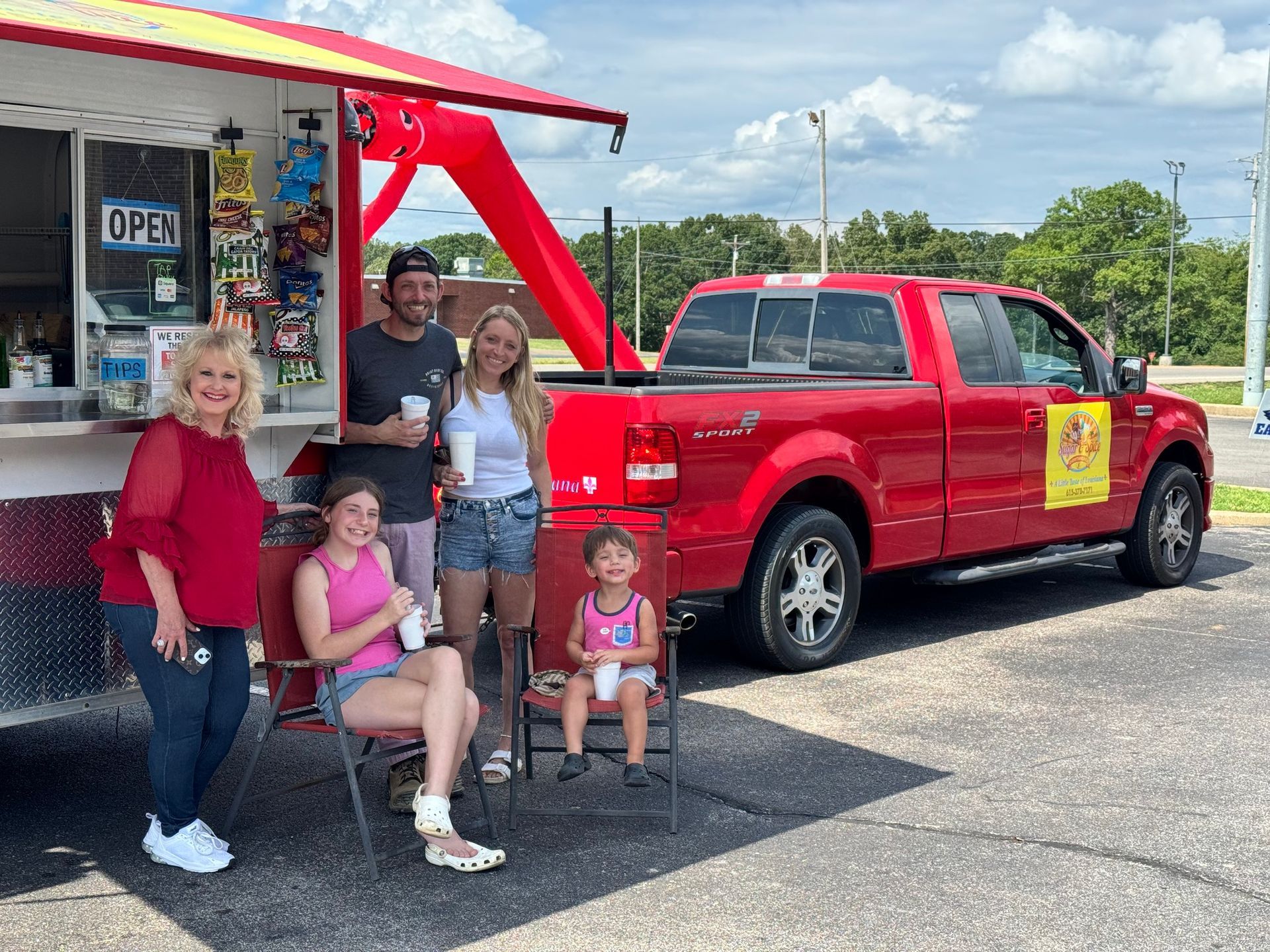 Group of people by a red food stand and truck
