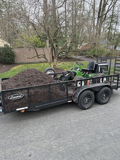 A trailer with a tractor on it is parked on the side of the road.