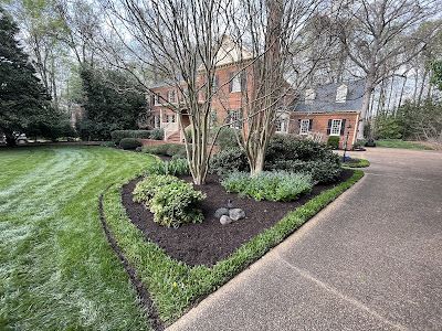 A large brick house with a lush green lawn and a driveway leading to it.