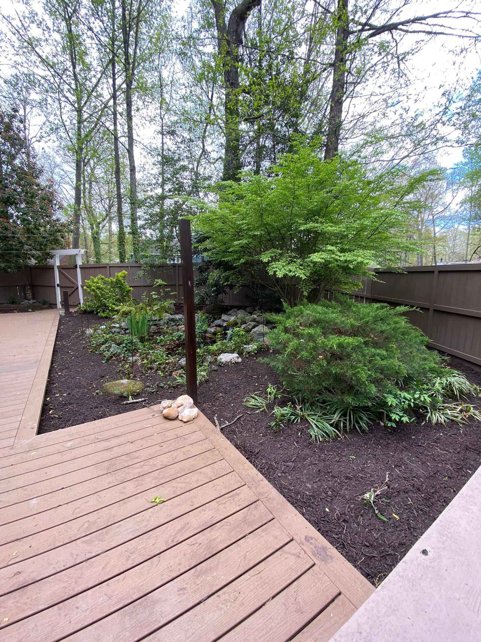 A wooden deck with a fence and trees in the background.