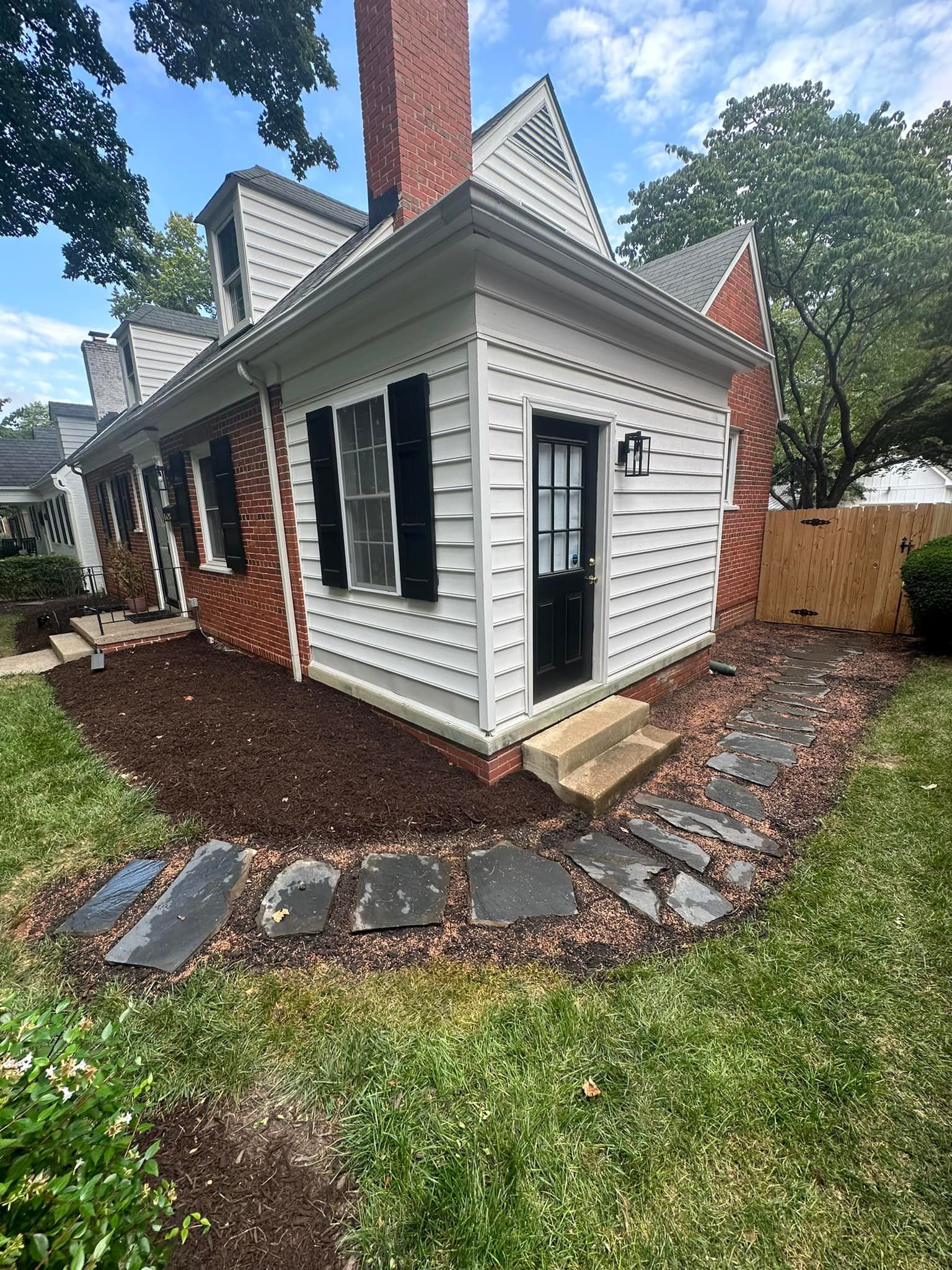 A white house with a brick chimney and a stone walkway in front of it.
