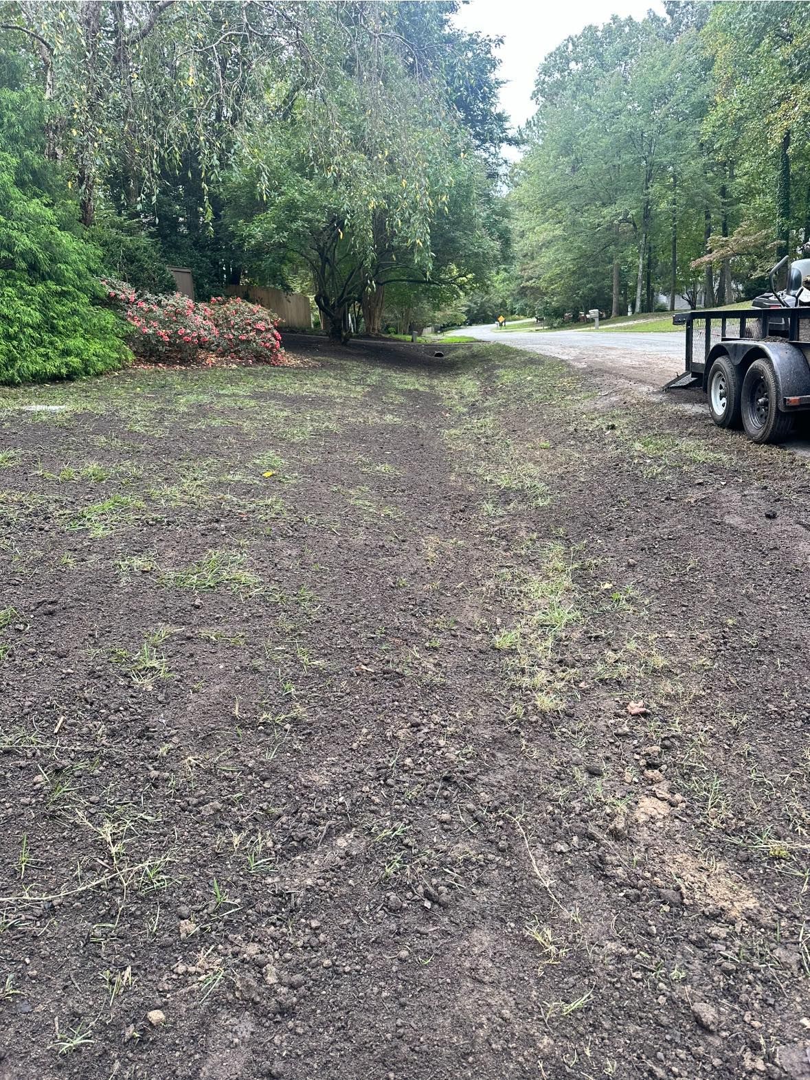 A trailer is parked in a dirt field next to a road.