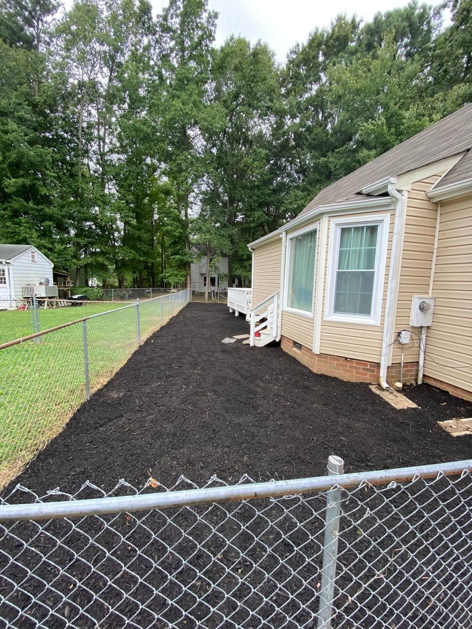 A chain link fence surrounds a house and a lawn.
