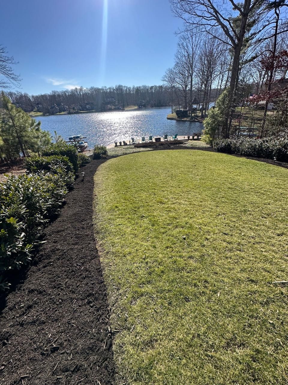 A large lush green lawn with a lake in the background.