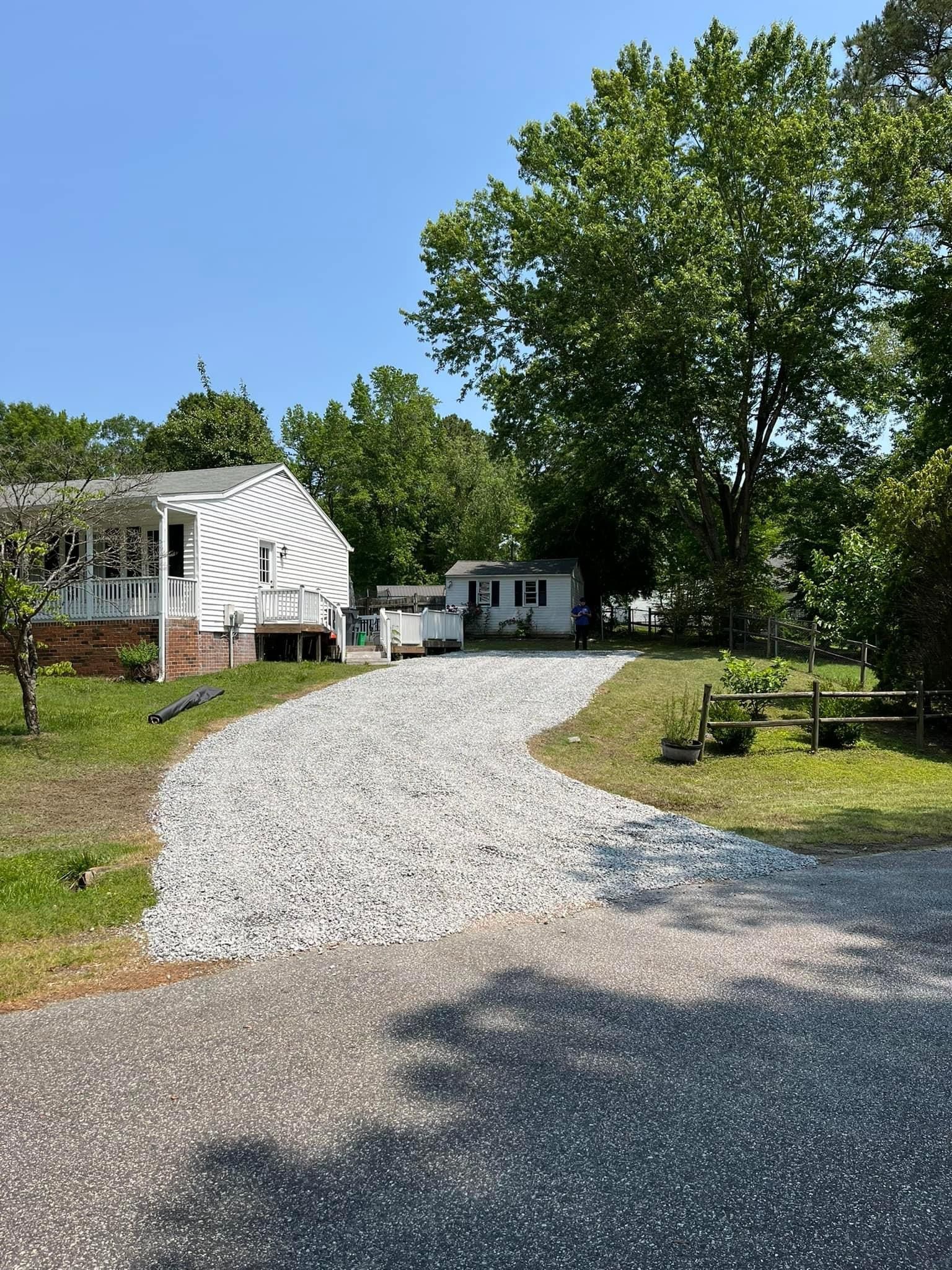 A gravel driveway leading to a white house