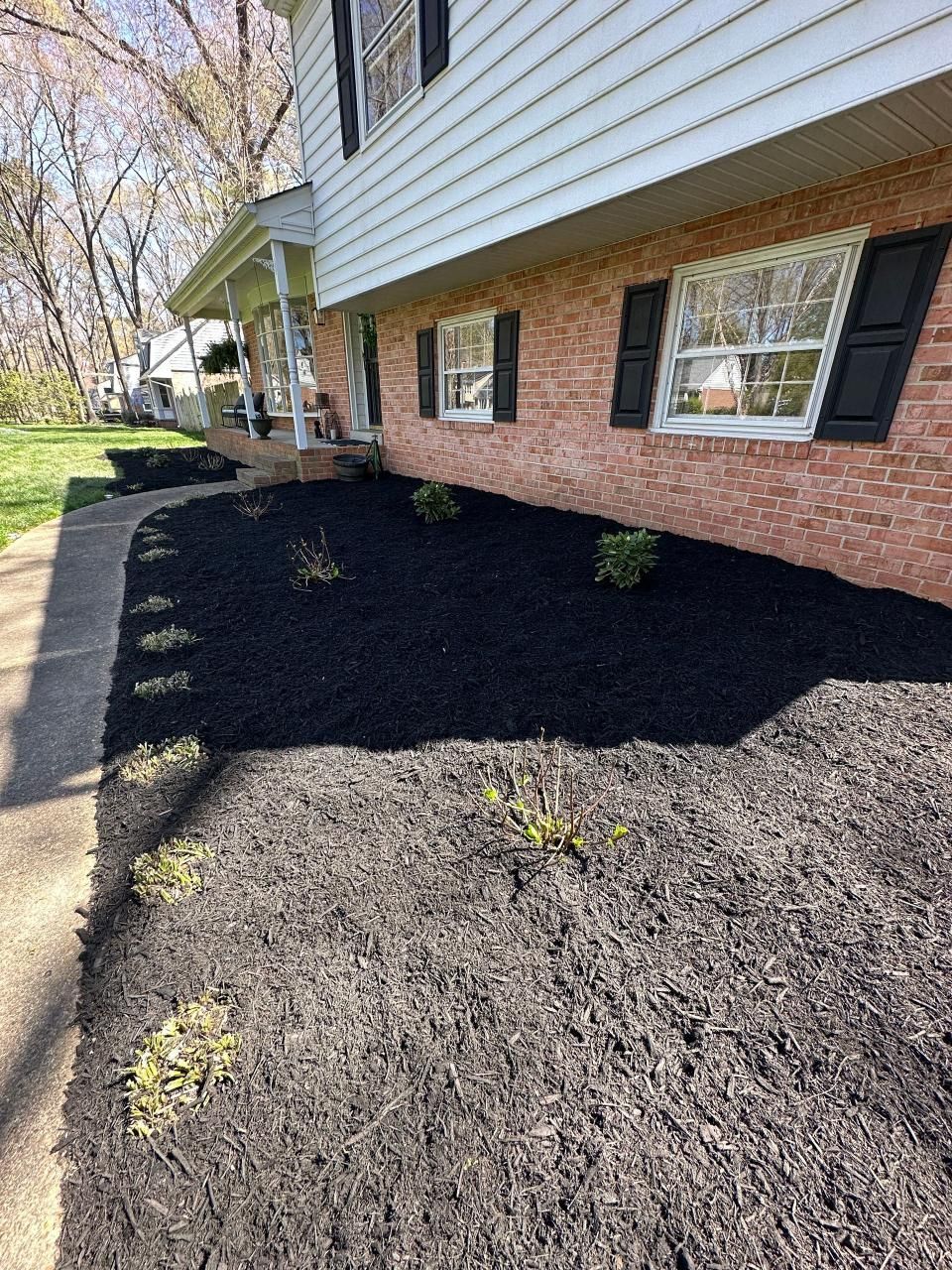 A brick house with black mulch in front of it