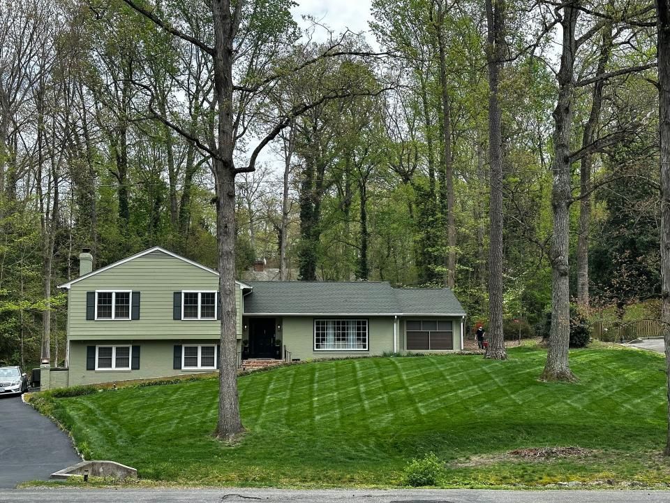 A green house with a lush green lawn in front of it