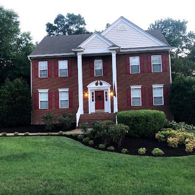 A large brick house with red shutters and white trim