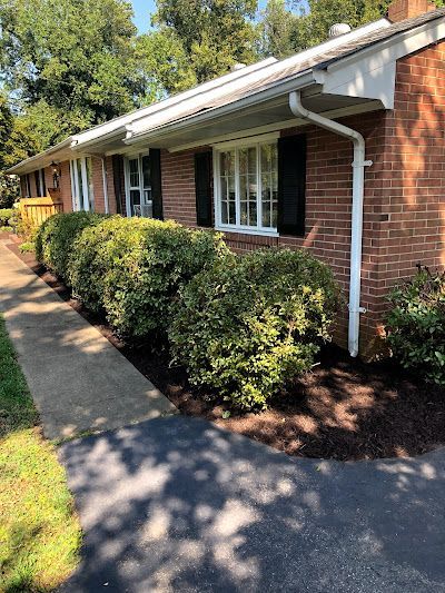 A brick house with black shutters and a walkway leading to it.