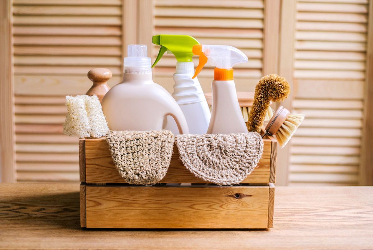 A wooden box filled with cleaning supplies on a wooden table.
