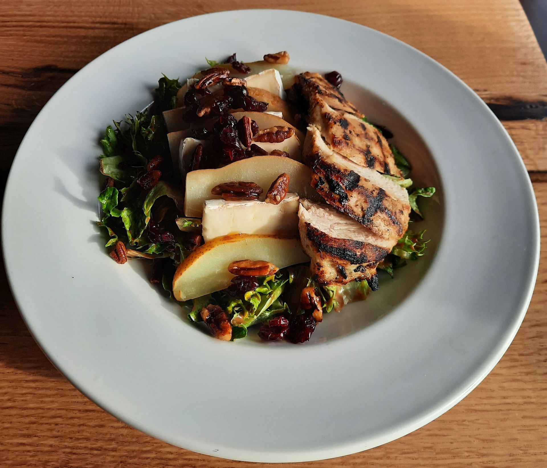 Salad with strawberries, blueberries, feta, and nuts on a white plate.