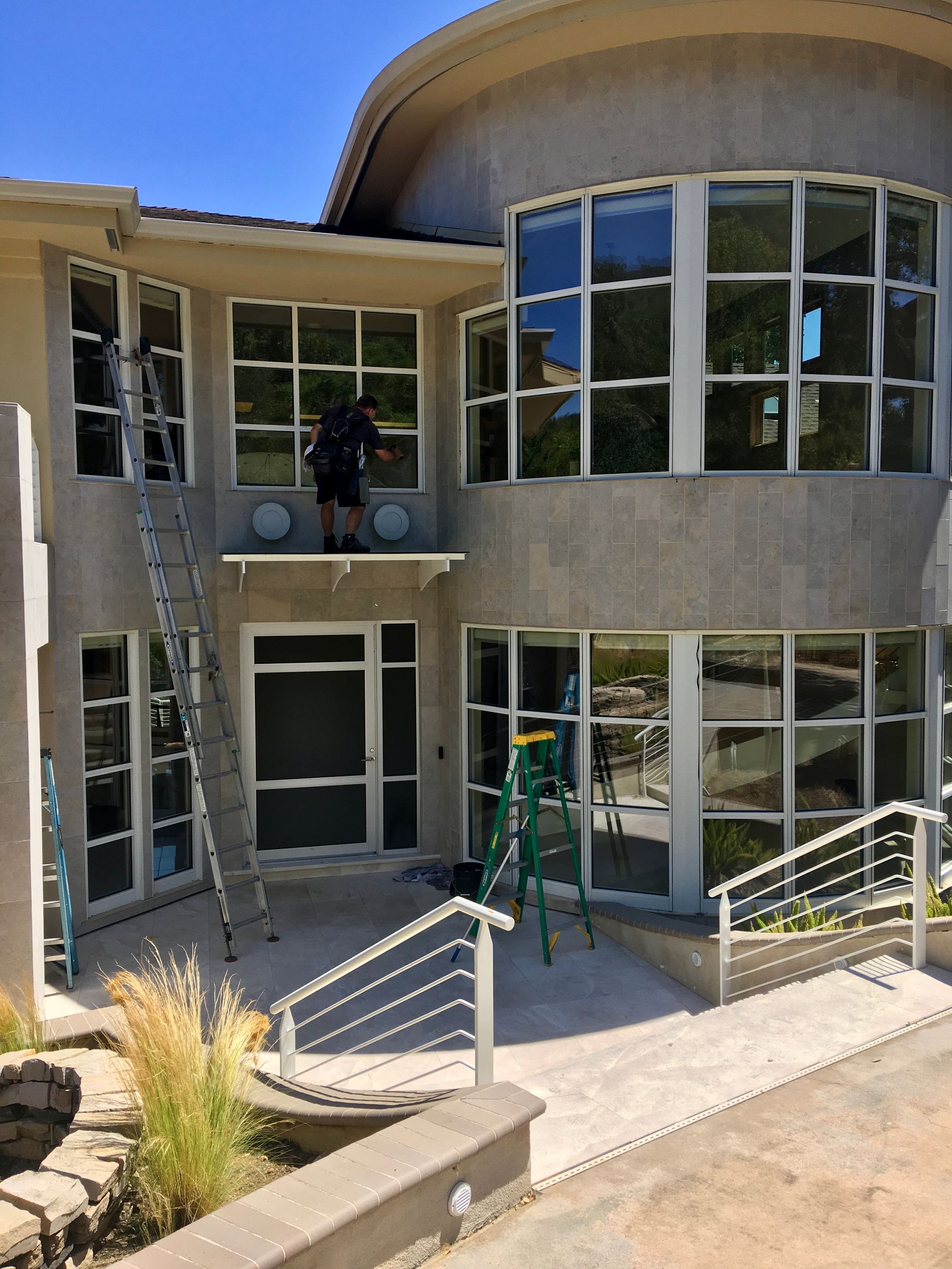 A man is standing on top of a roof with tools.