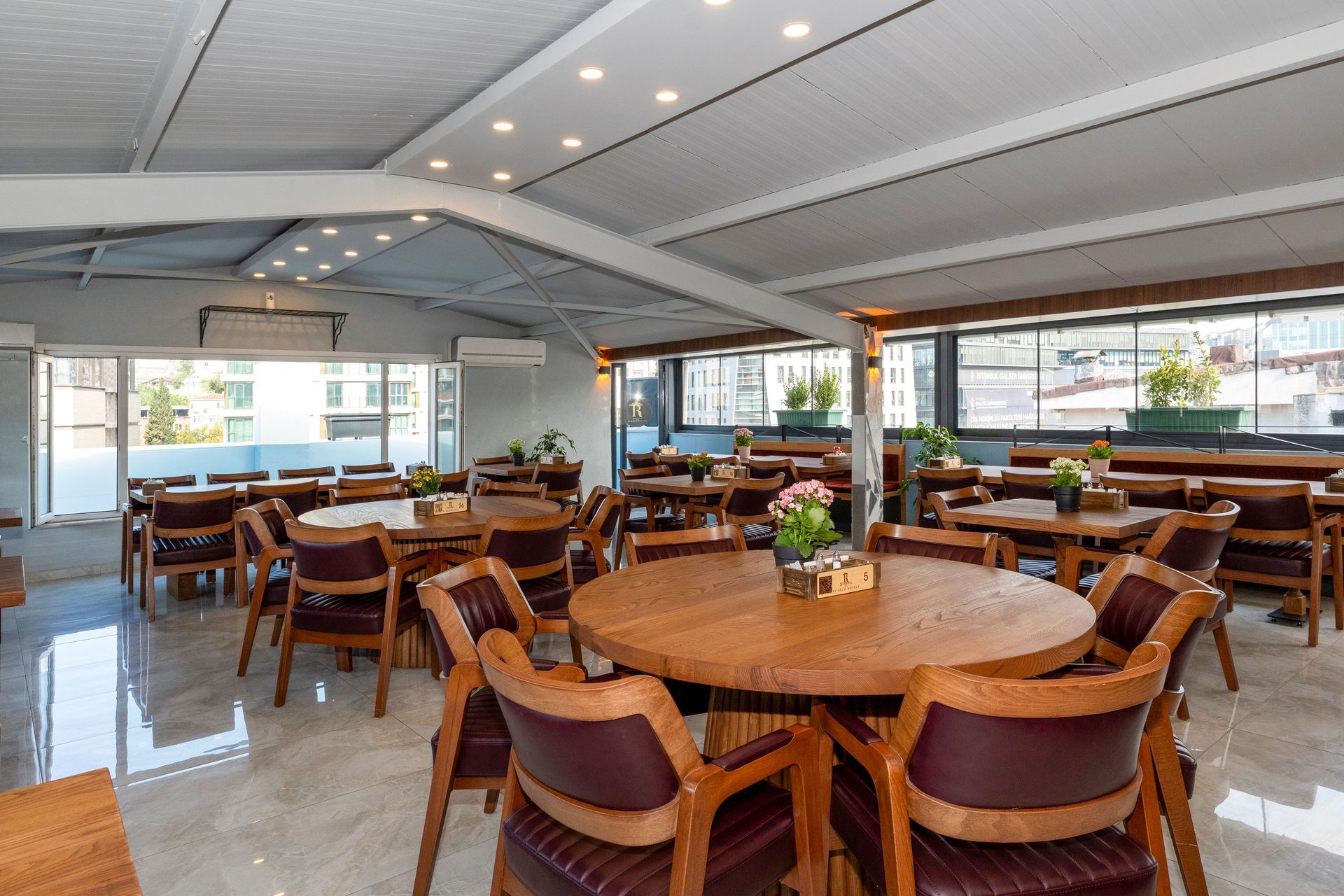 Istanbul By Rich Hotel | Restaurant dining area with wooden tables and chairs, under a retractable roof.
