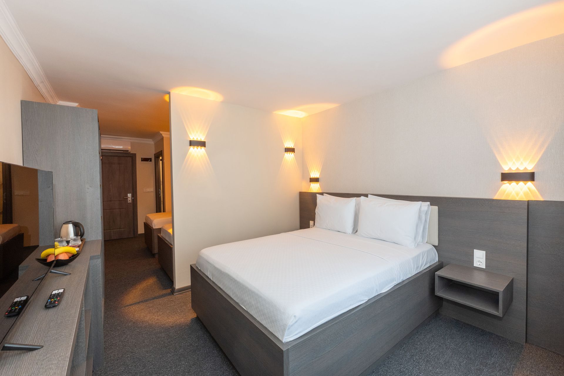Istanbul By Rich Hotel | Hotel bedroom with a double bed, TV, and decorative wall lights.
