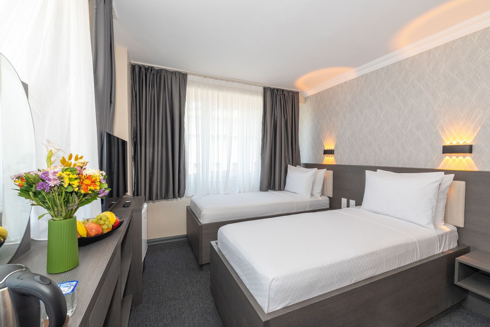 Istanbul Rich Hotel | Hotel room with two twin beds, gray curtains, and a vase of flowers.