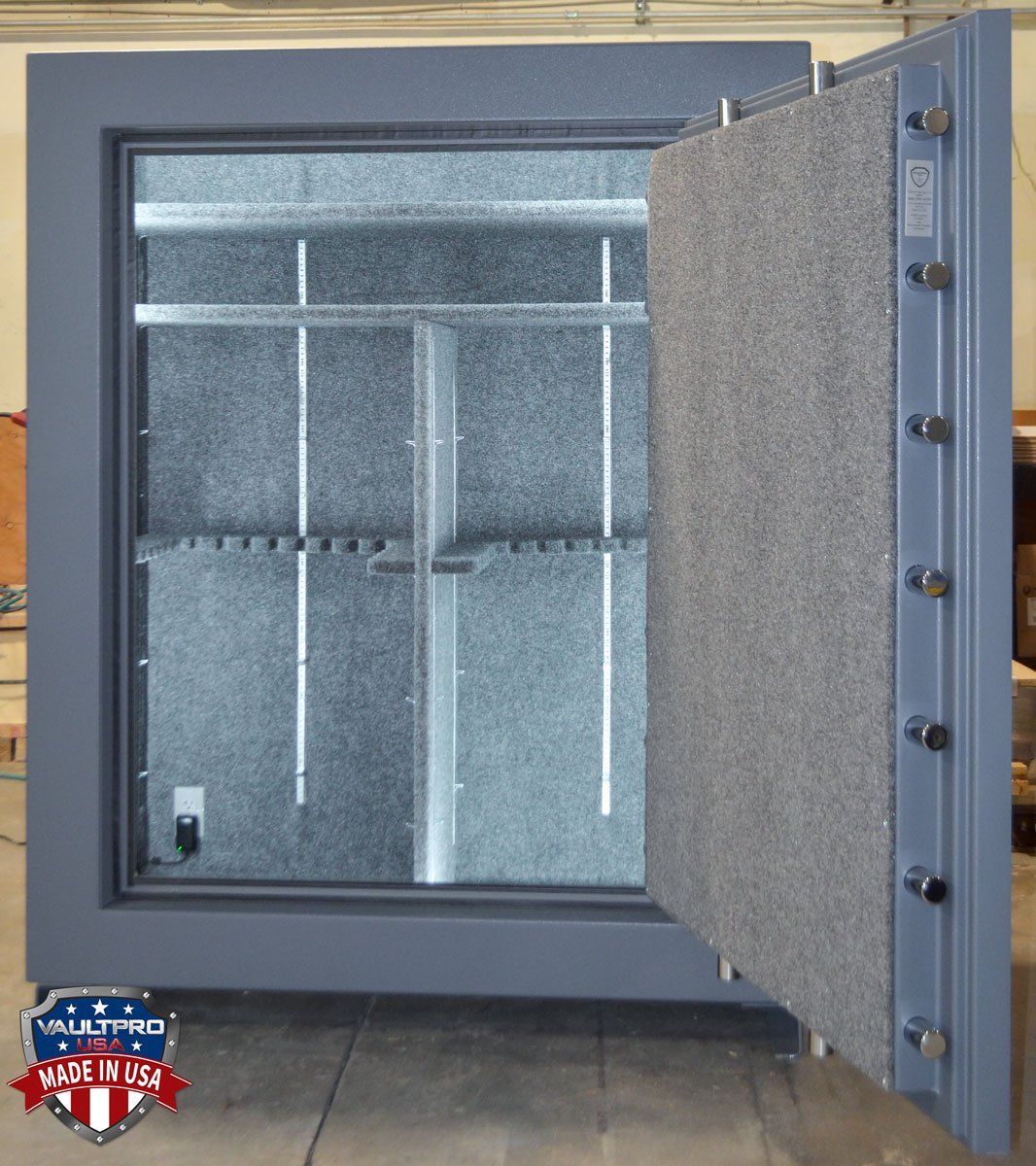 Open gray gun safe interior. Shelves, gun rack, gray felt lining. 