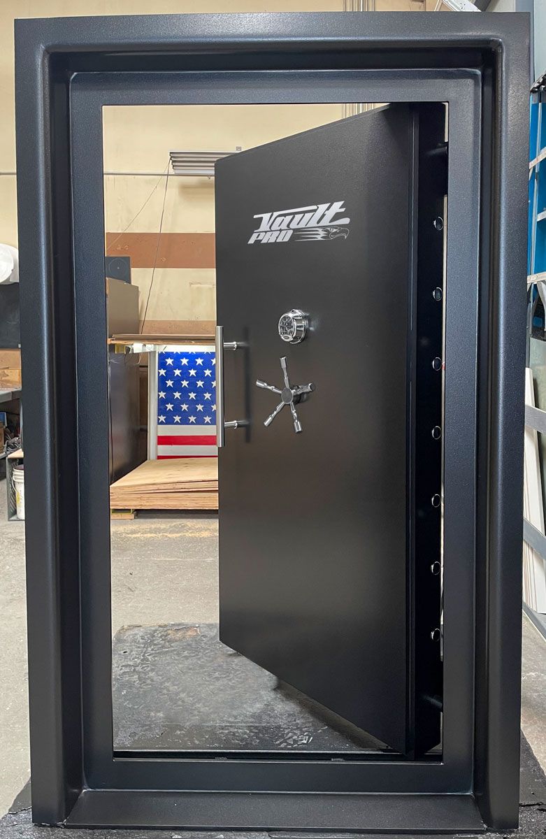 A matte black vault door partially open in a metal frame, featuring a silver handle, locking wheel, and logo.