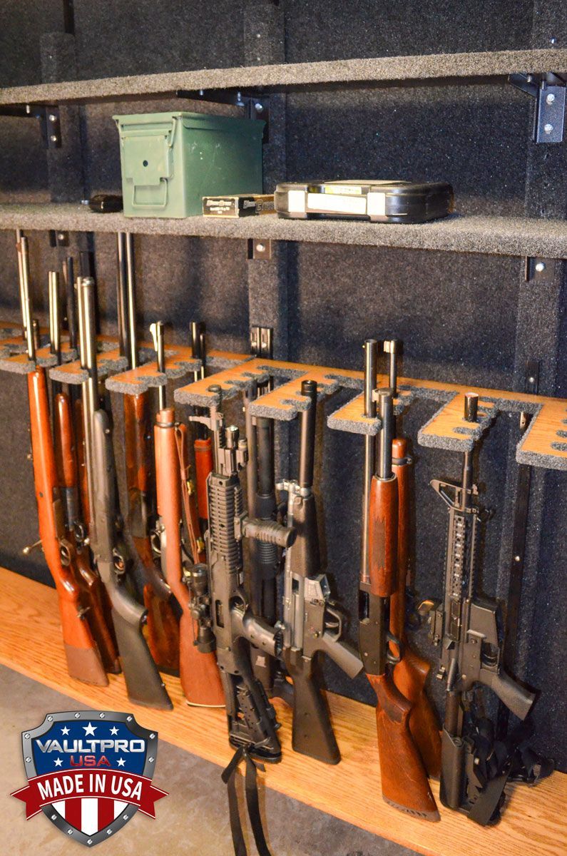 Long gun racks vertical in vault room with guns, shelves above. mounted.