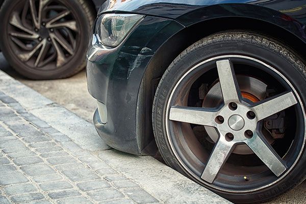 Black car parked close to curb. Front tire and rim visible. | Auto Clinic Care