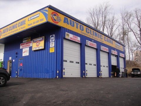 Blue Auto Clinic Care building with four garage bays; dark car parked nearby. | Auto Clinic Care
