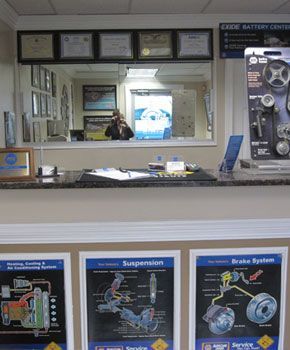 Auto shop reception desk with posters, window, and employee. | Auto Clinic Care