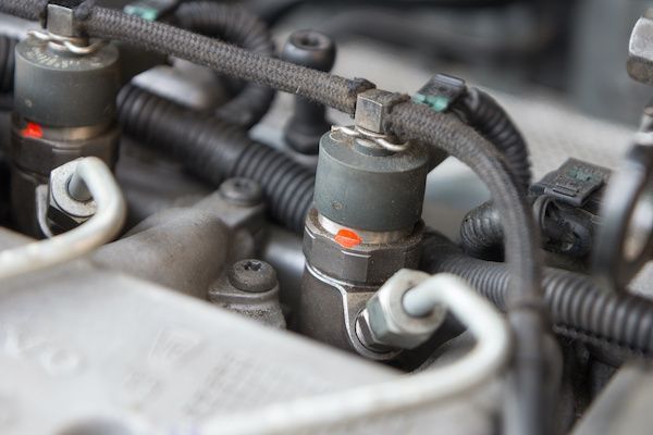 Close-up of car engine fuel injectors, with connected hoses and tubes. | Auto Clinic Care