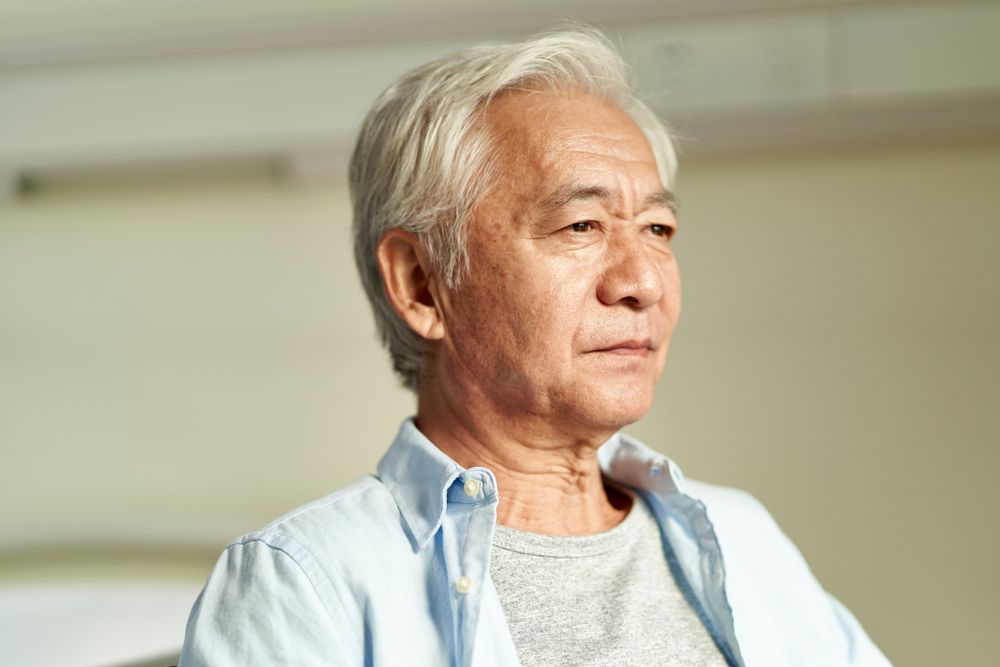 An Older Man Is Sitting On A Couch And Looking Away From The Camera — Aged Care in Tamworth, NSW