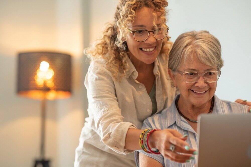 A Woman Is Helping An Older Woman Use A Laptop Computer — Aged Care in Tamworth, NSW