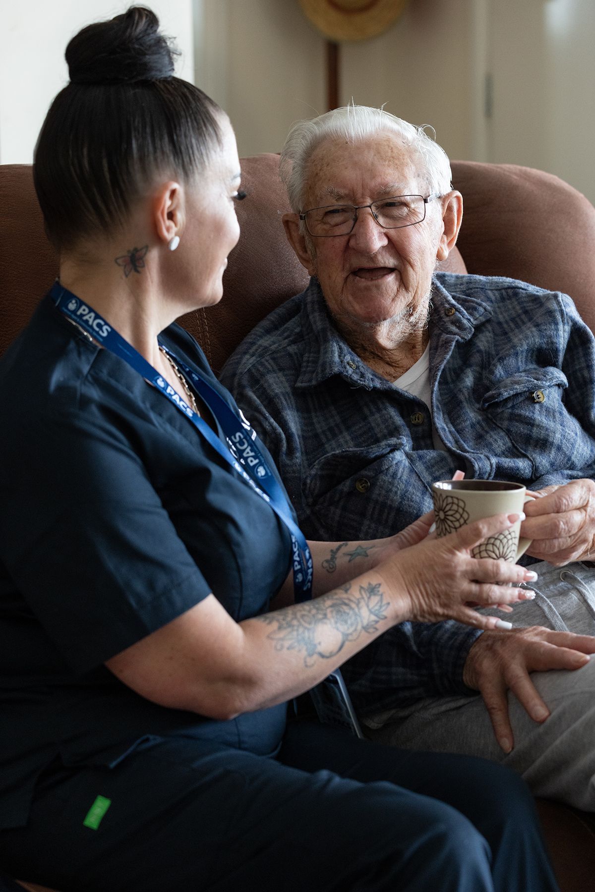 Woman in a Blue Shirt Points at Something in a Book While Sitting — Premium Aged & Community Services In Tamworth, NSW
