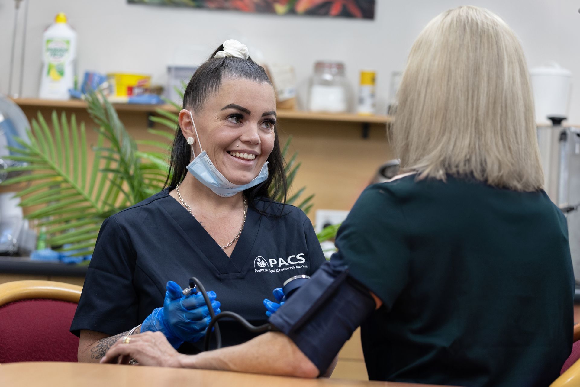 Woman in a Blue Shirt Points at Something in a Book While Sitting — Premium Aged & Community Services In Tamworth, NSW