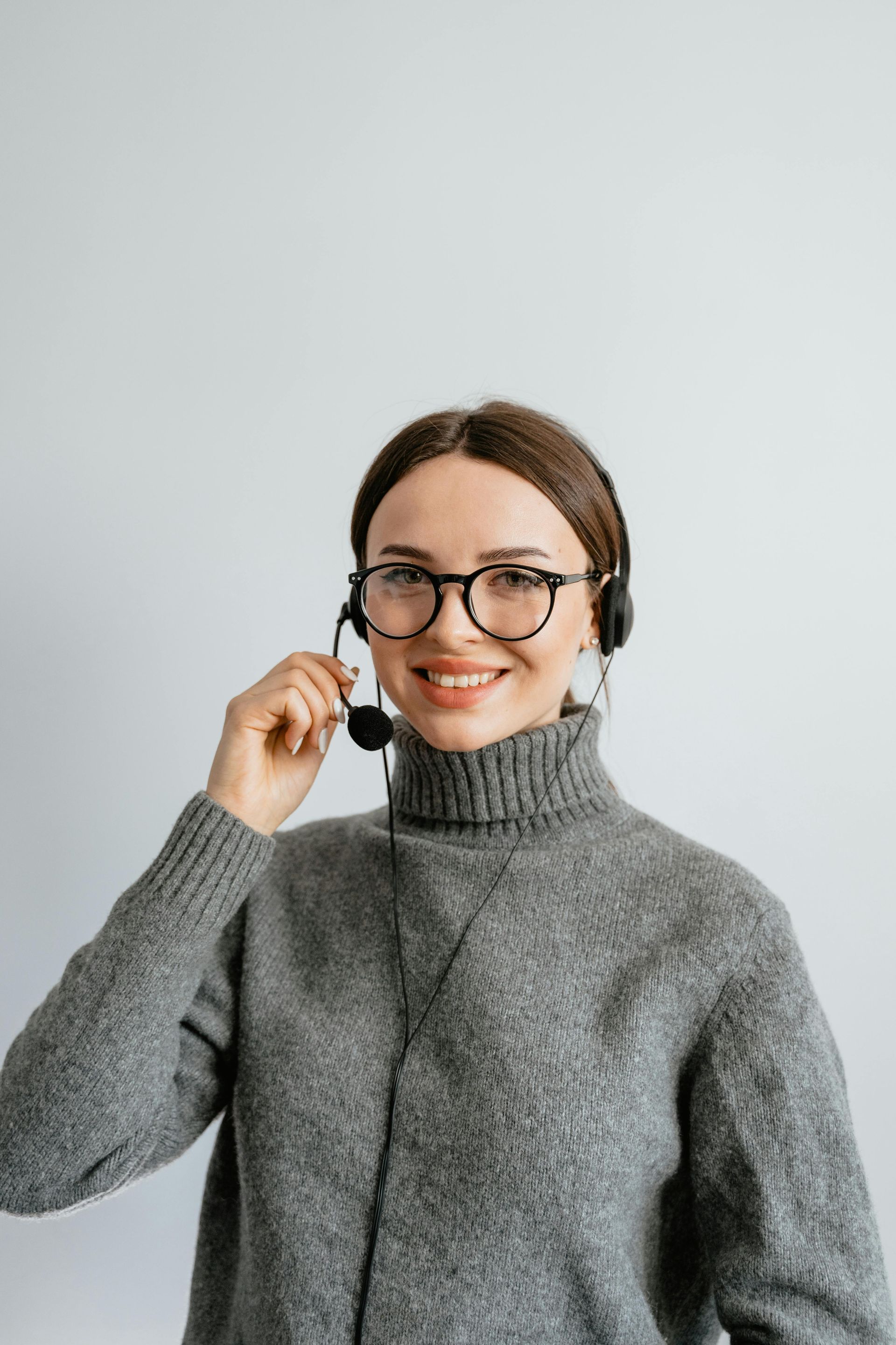 A Woman Wearing Glasses And A Headset Is Smiling — Aged Care in Tamworth, NSW
