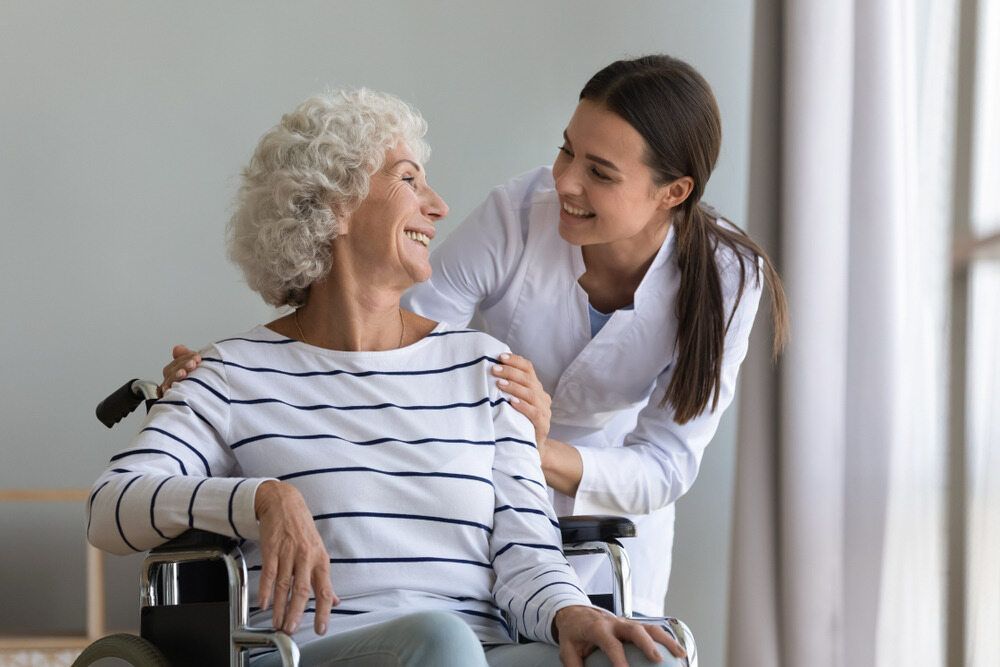 A Nurse Is Talking To An Elderly Woman In A Wheelchair — Aged Care in Tamworth, NSW