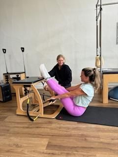 A woman is doing exercises on a pilates machine in a gym.