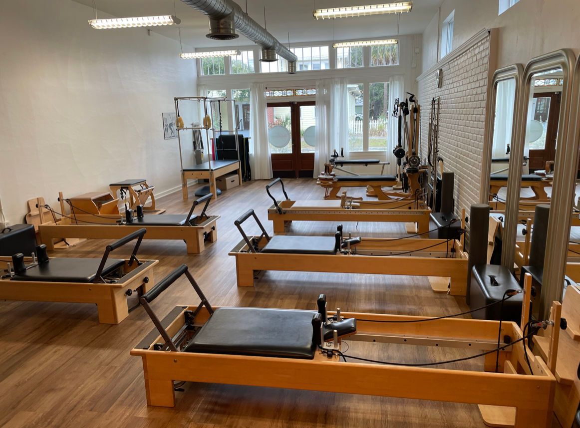 a row of pilates machines are lined up in a Pilates studio