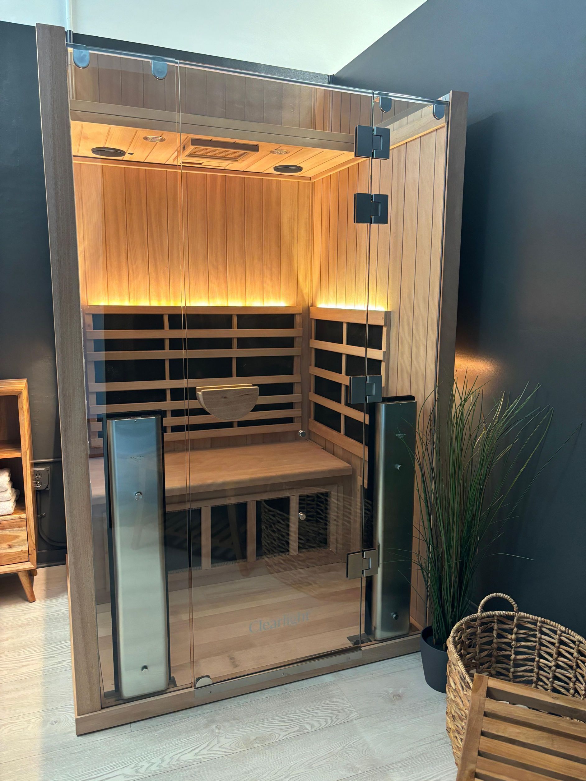 A wooden sauna is sitting in a room next to a basket.