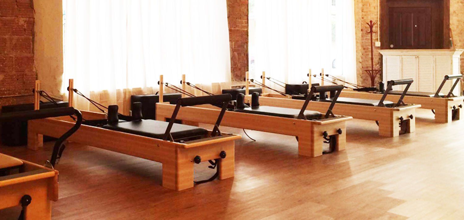 a row of wooden pilates machines in a pilates studio